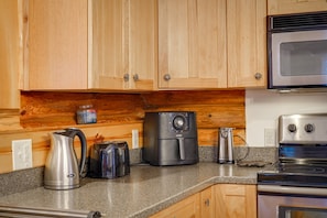 Una cocina con armarios de madera, microondas, cafetera y tostadora.
