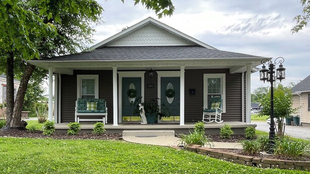 A two-story house with a front porch, a mailbox, and a street lamp.