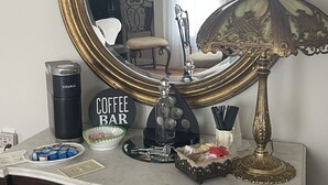 A coffee bar setup with a mirror, a Keurig coffee maker, a coffee mug, and a decorative lamp.