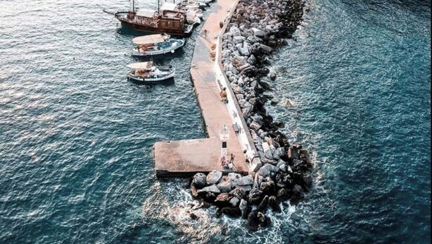A coastal town with a rocky pier extending into the sea, lined with boats and surrounded by white buildings. - Villa Vlychada w. Pool, Jacuzzi & Sea Views (9QXM+554 Vlichada, Greece)
