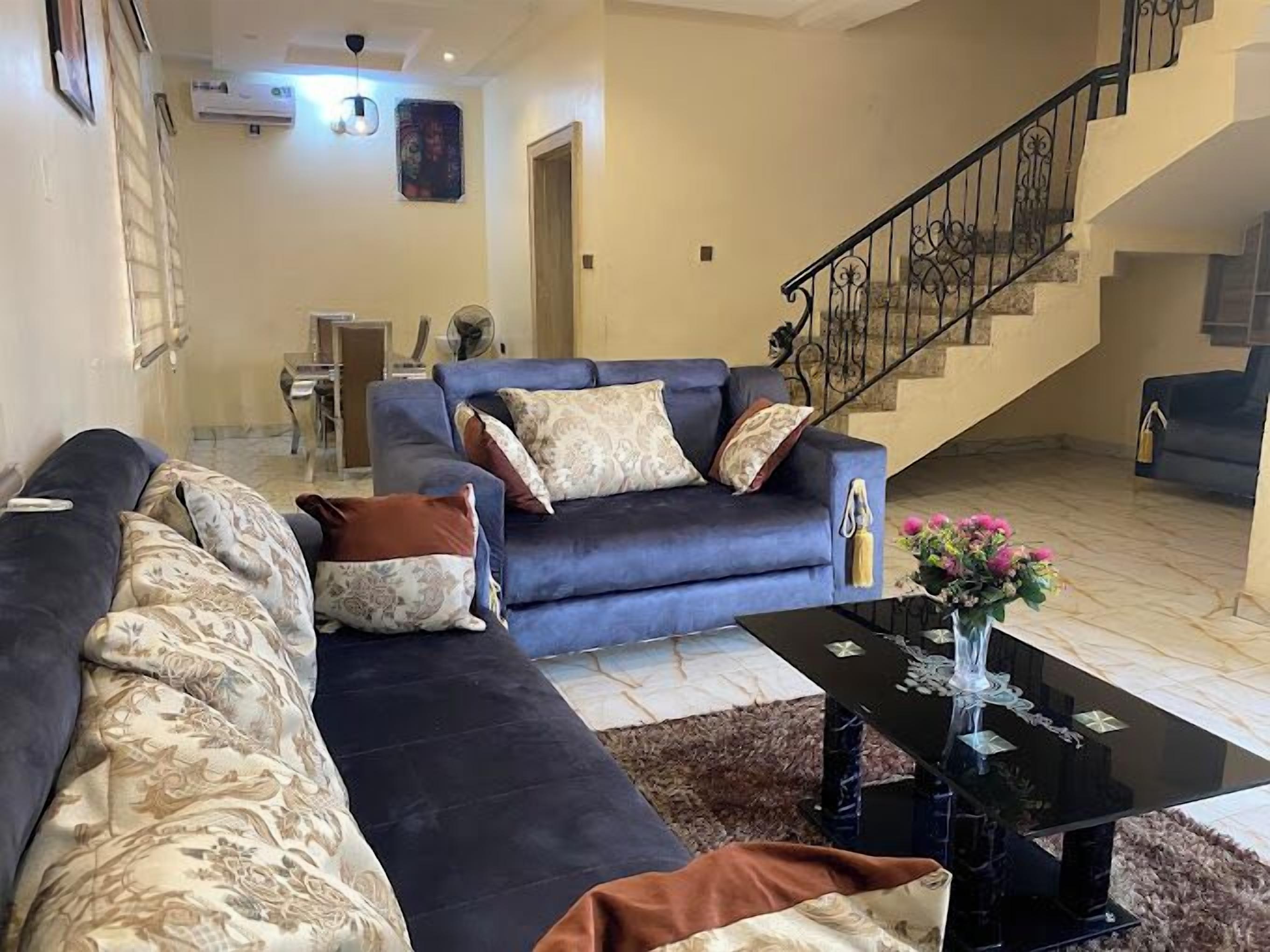 A living room with a dark blue sofa set, a coffee table, and a staircase.