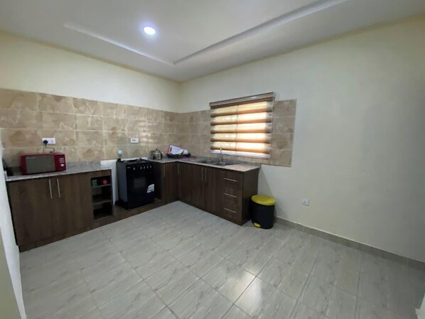 A compact kitchen with a microwave, stove, and sink. - Plot 35 Apartments (Owerri)