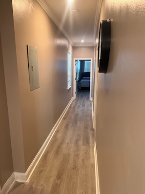 A hallway with beige walls, wooden flooring, and a door leading to a bedroom. - Charming 3-bedroom house in fabulous New Orleans with WiFi, AC (New Orleans)