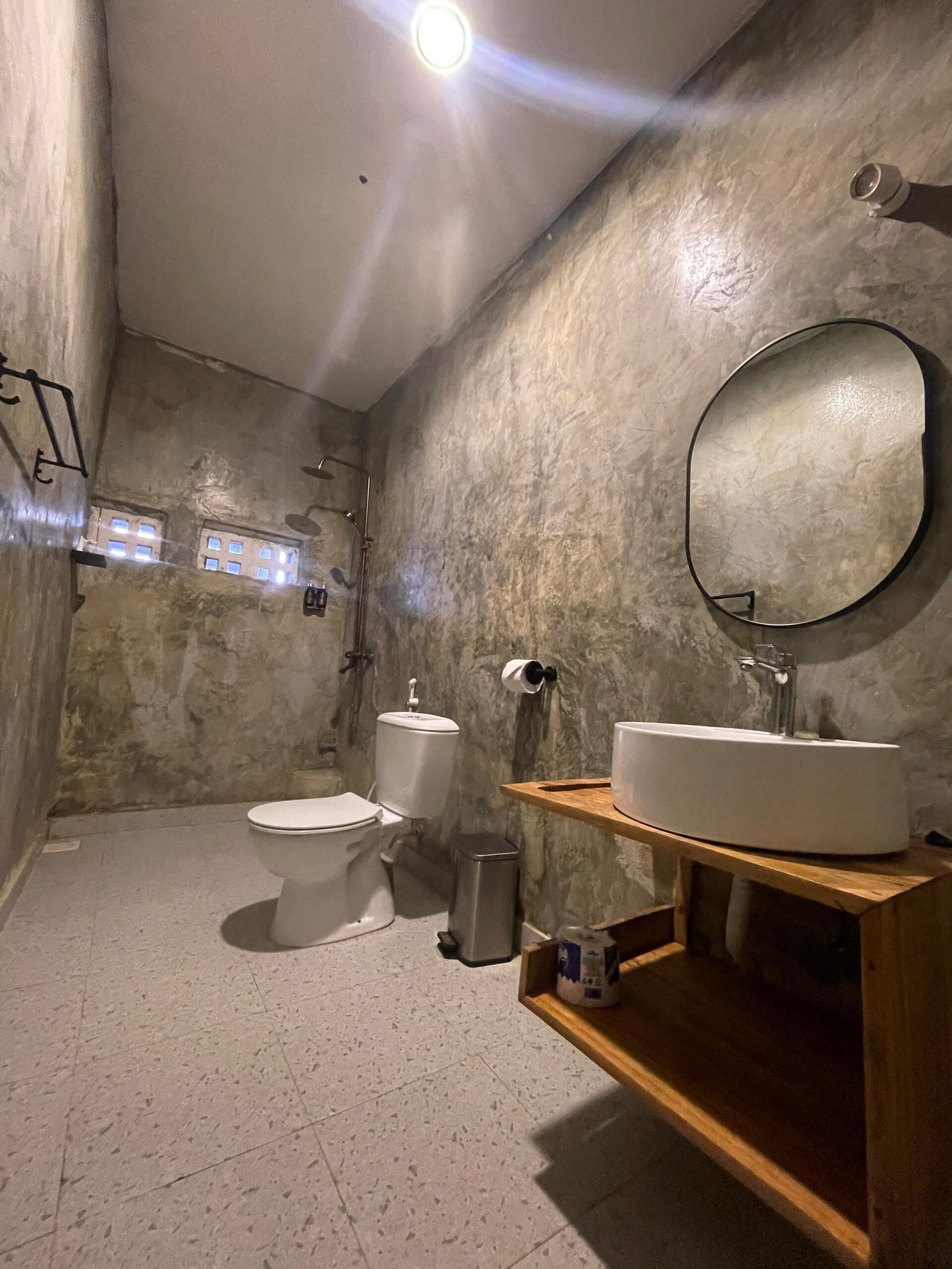 A bathroom with a toilet, sink, mirror, and a small window.