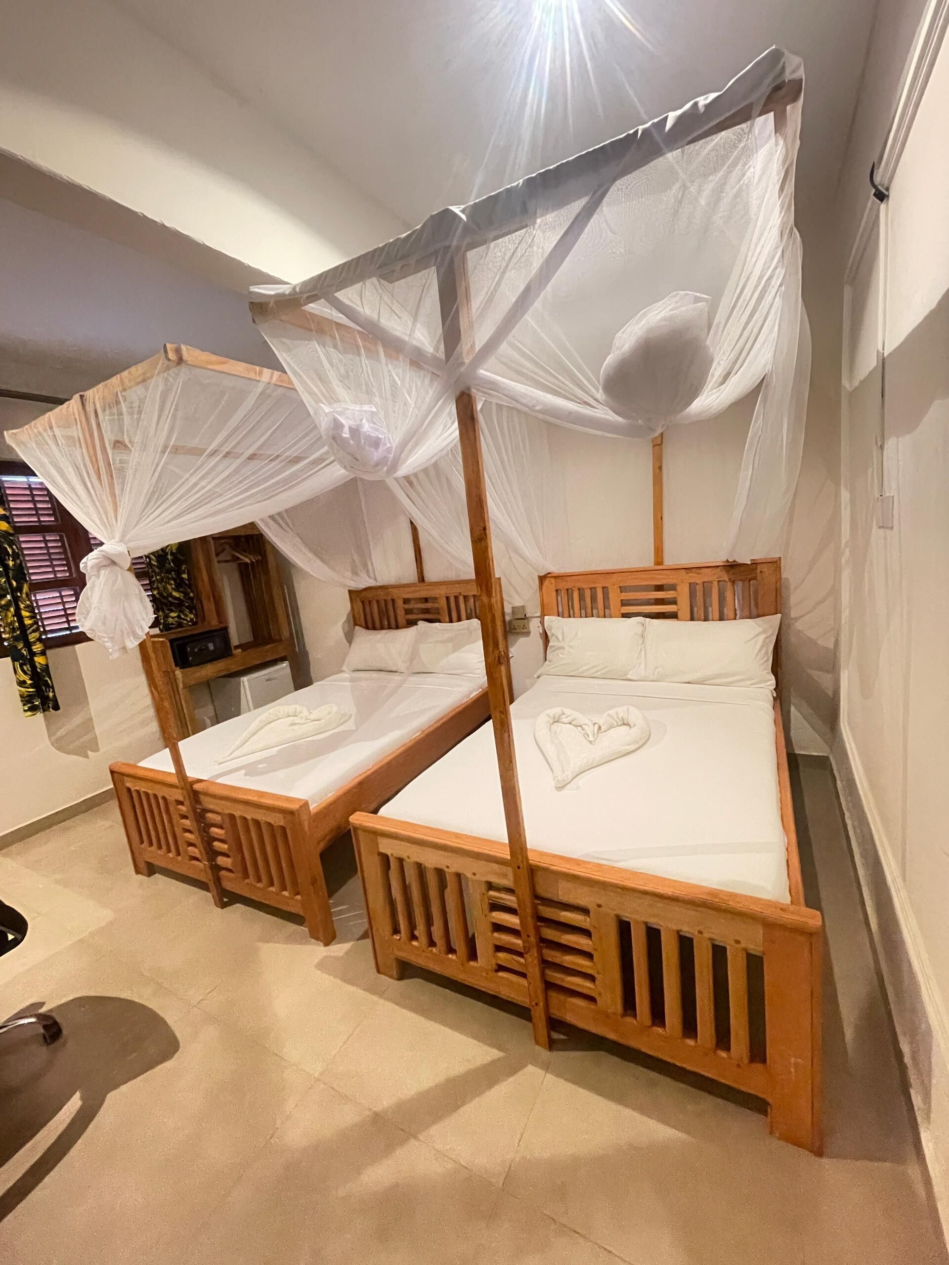 A room with two wooden beds, each with a canopy.