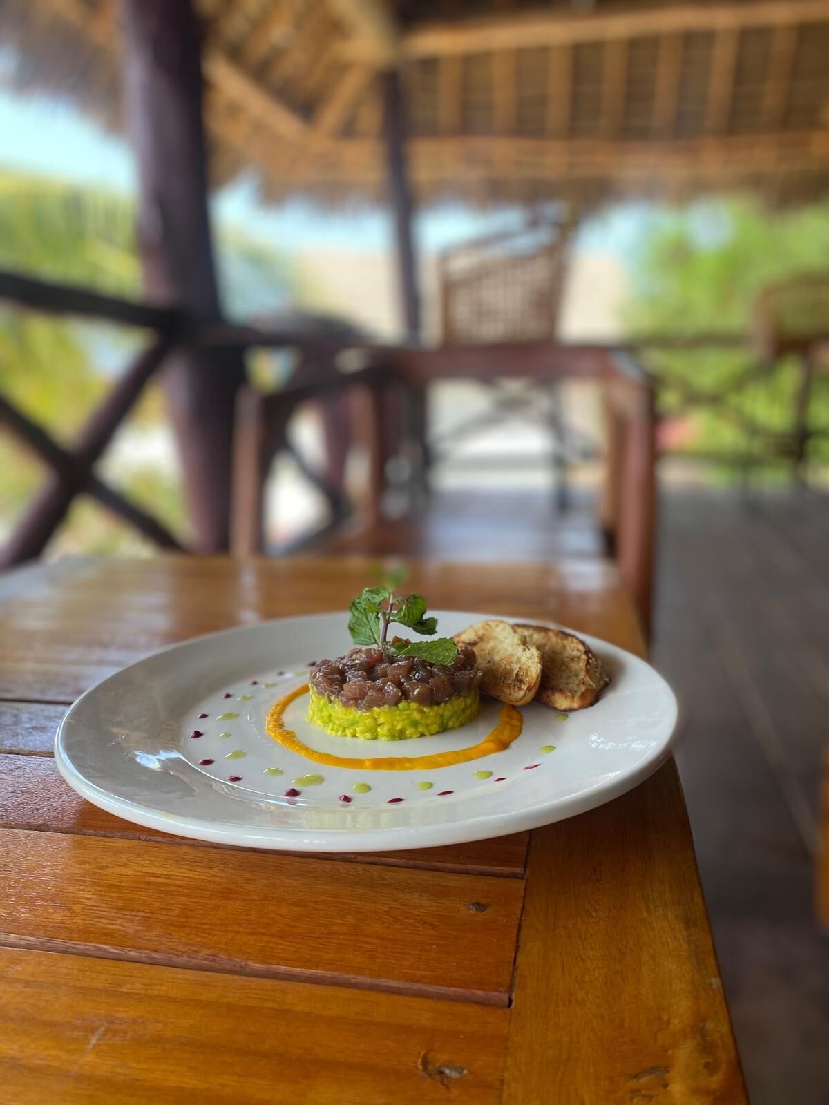 A plate of food on a wooden table with a blurred outdoor background.
