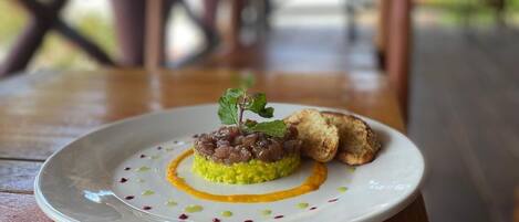 A plate of food on a wooden table with a blurred outdoor background.
