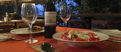 Ein gedeckter Tisch mit einem Essen, einer Flasche Culembur Wein, zwei Weingläsern und Tellern voller Speisen.