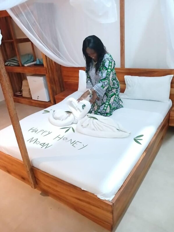 Un lit à baldaquin, une table de chevet et une étagère avec des vêtements pliés et un petit appareil électroménager blanc.