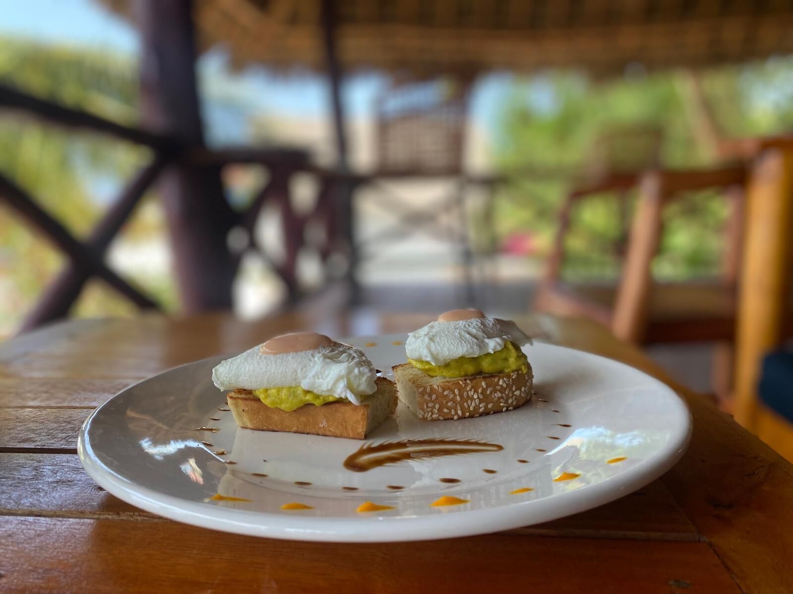 Ein Teller mit zwei Avocado-Toast-Sandwiches auf einem Holztisch.