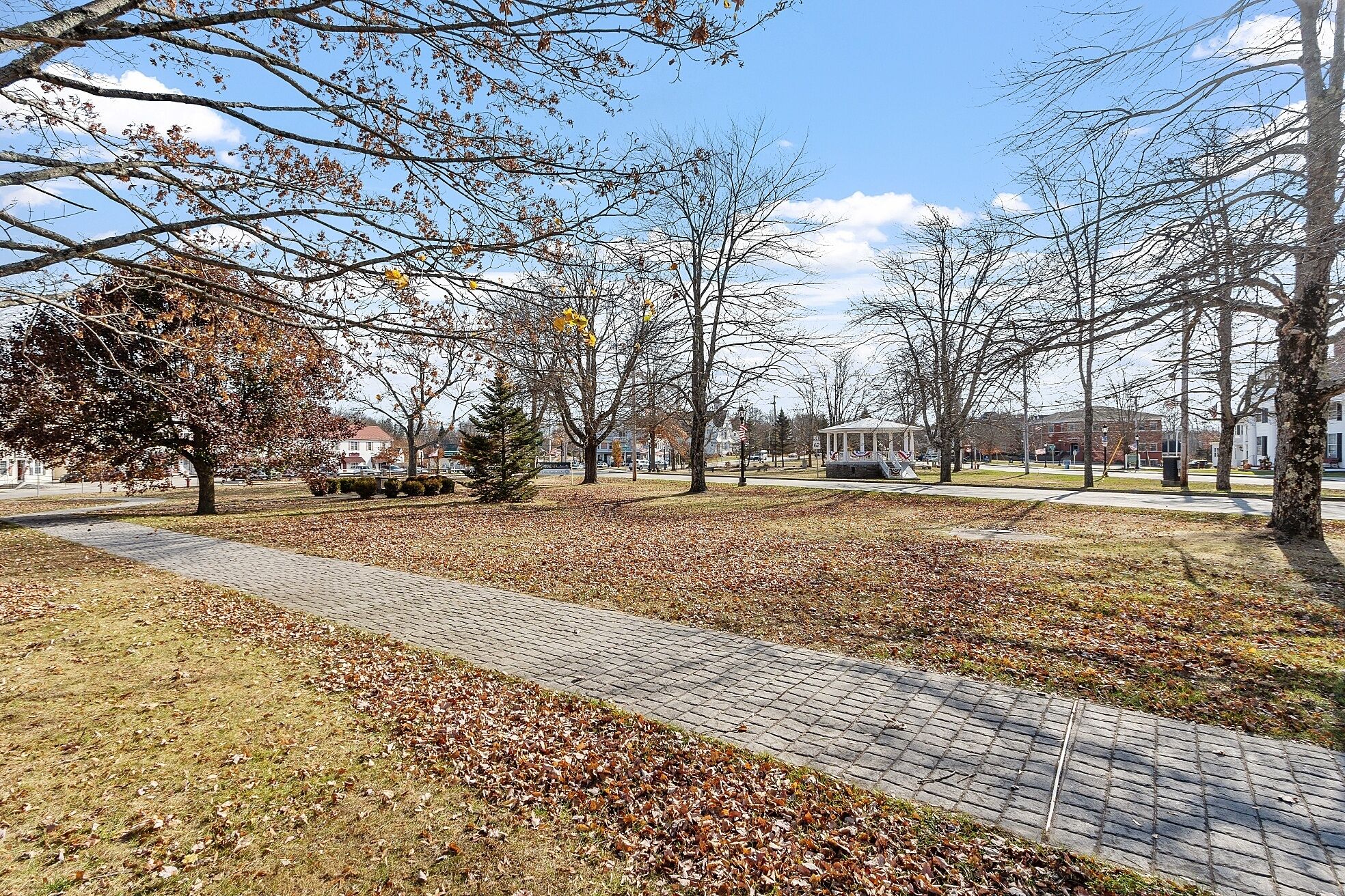 Un parc doté d’un sentier dallé, d’arbres et d’un kiosque.