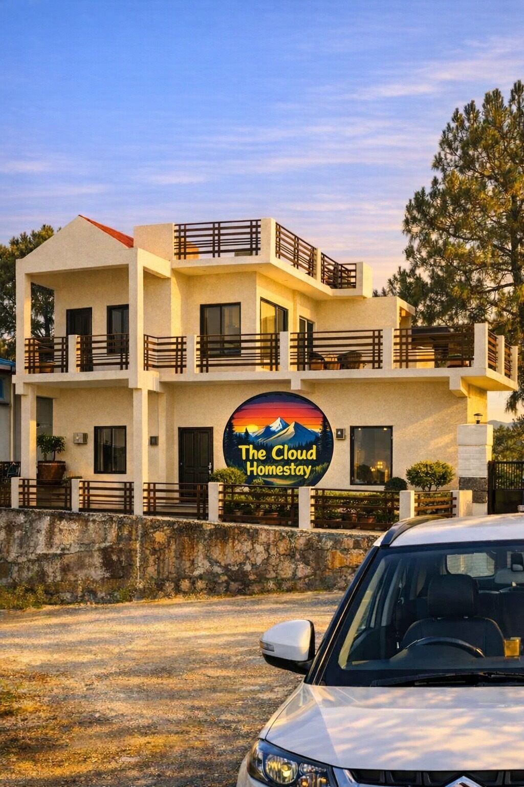 Un immeuble à plusieurs étages doté de balcons, une enseigne indiquant « The Cloud Homestay », et une voiture garée devant.