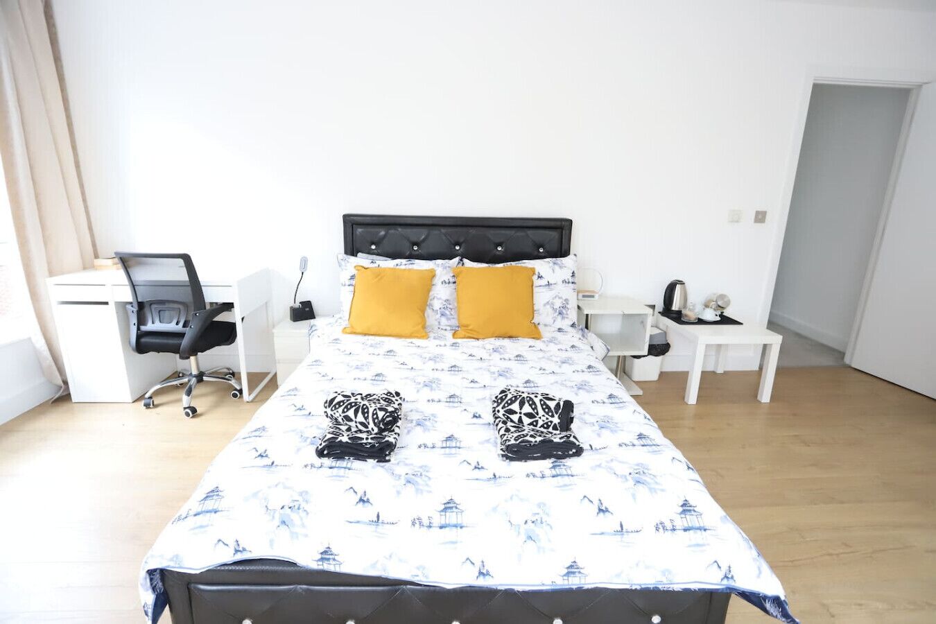 A neatly arranged bedroom with a bed, two bedside tables, a desk, and a chair.