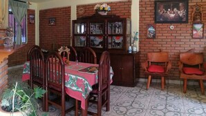 A dining area with a brick wall, a wooden cabinet with glass doors, and a tiled floor. - Beautiful vacation home. Familiar, well located and very cozy, (Morelia)