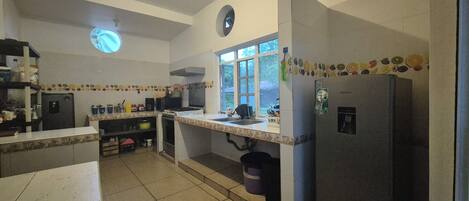 Una cocina con refrigerador, estufa, lavaplatos y ventana.