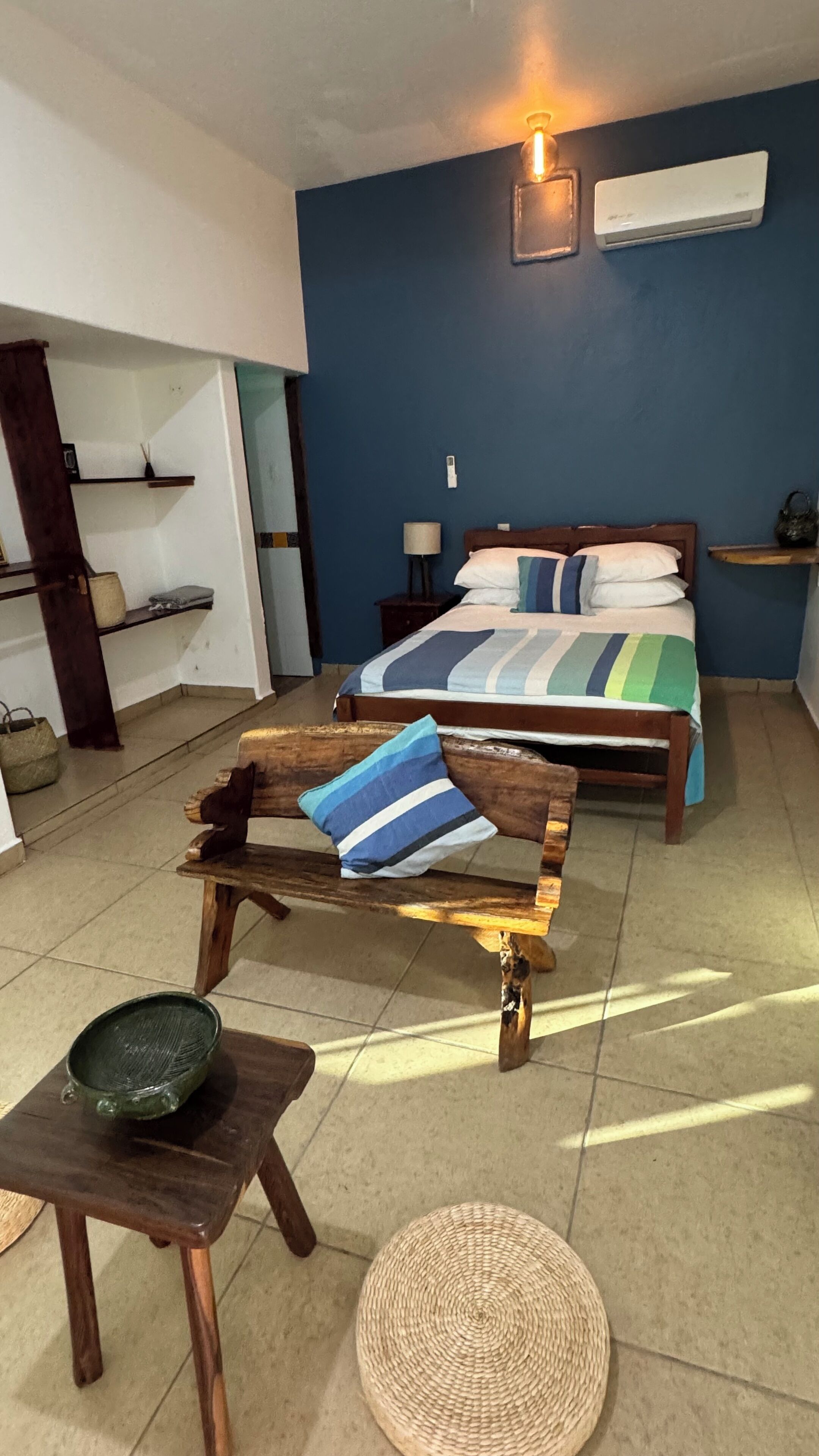 A bedroom with a bed, bedside tables, a lamp, and a small wooden table with a bowl.