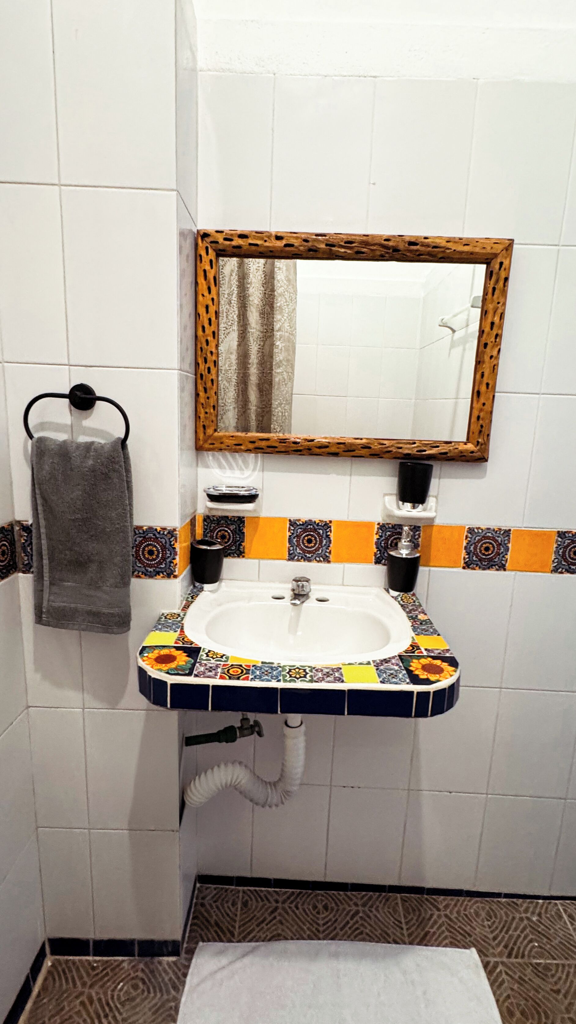 A bathroom with a white sink, a mirror with a wooden frame, and a towel hanging on a hook.