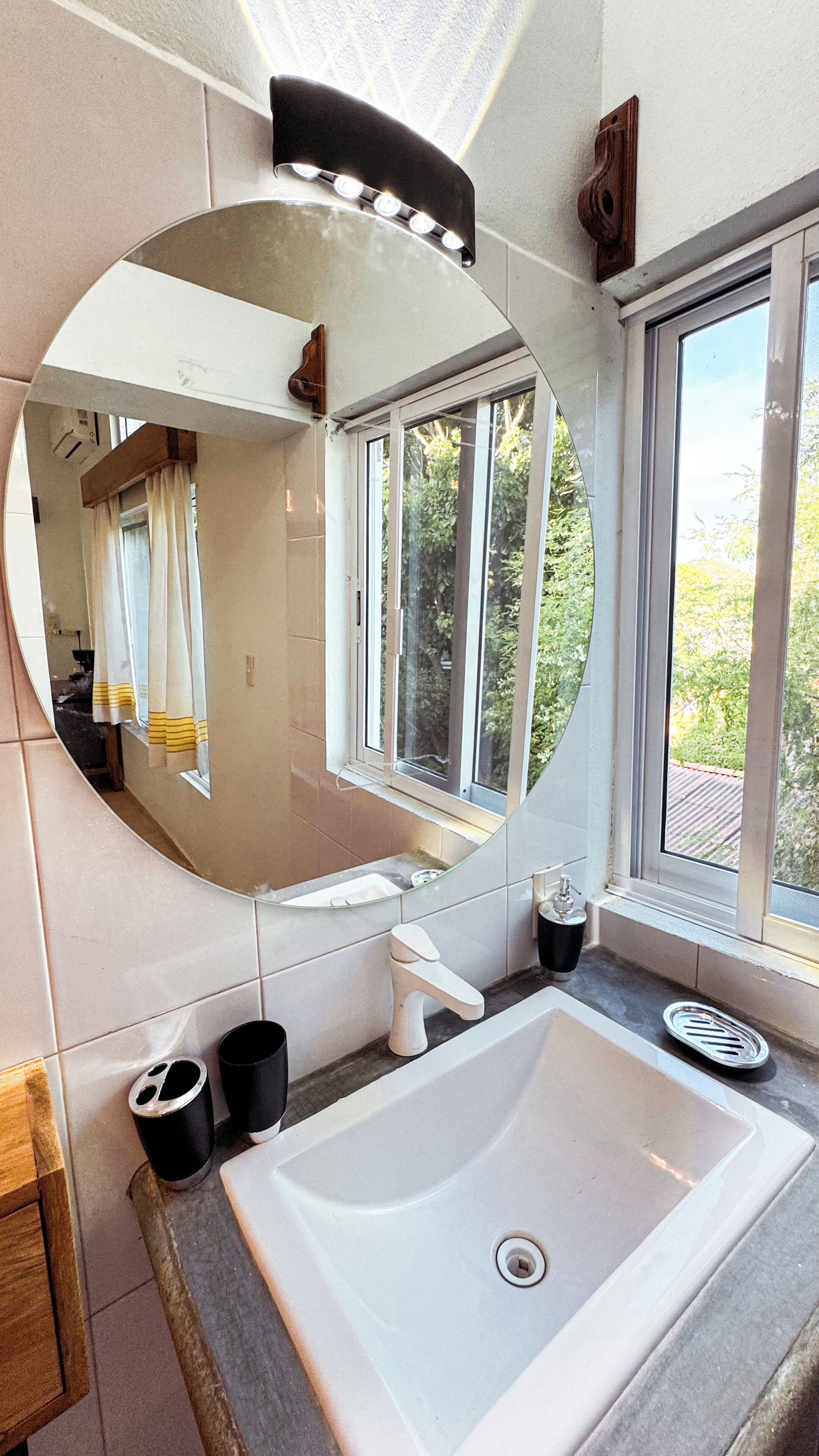 A bathroom with a large mirror, a sink, and a window.