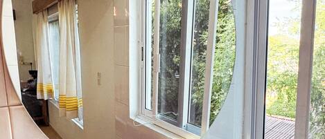 A bathroom with a large mirror, a sink, and a window.