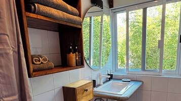 Une salle de bain équipée de toilettes, d’un lavabo et d’une fenêtre donnant sur un espace verdoyant.