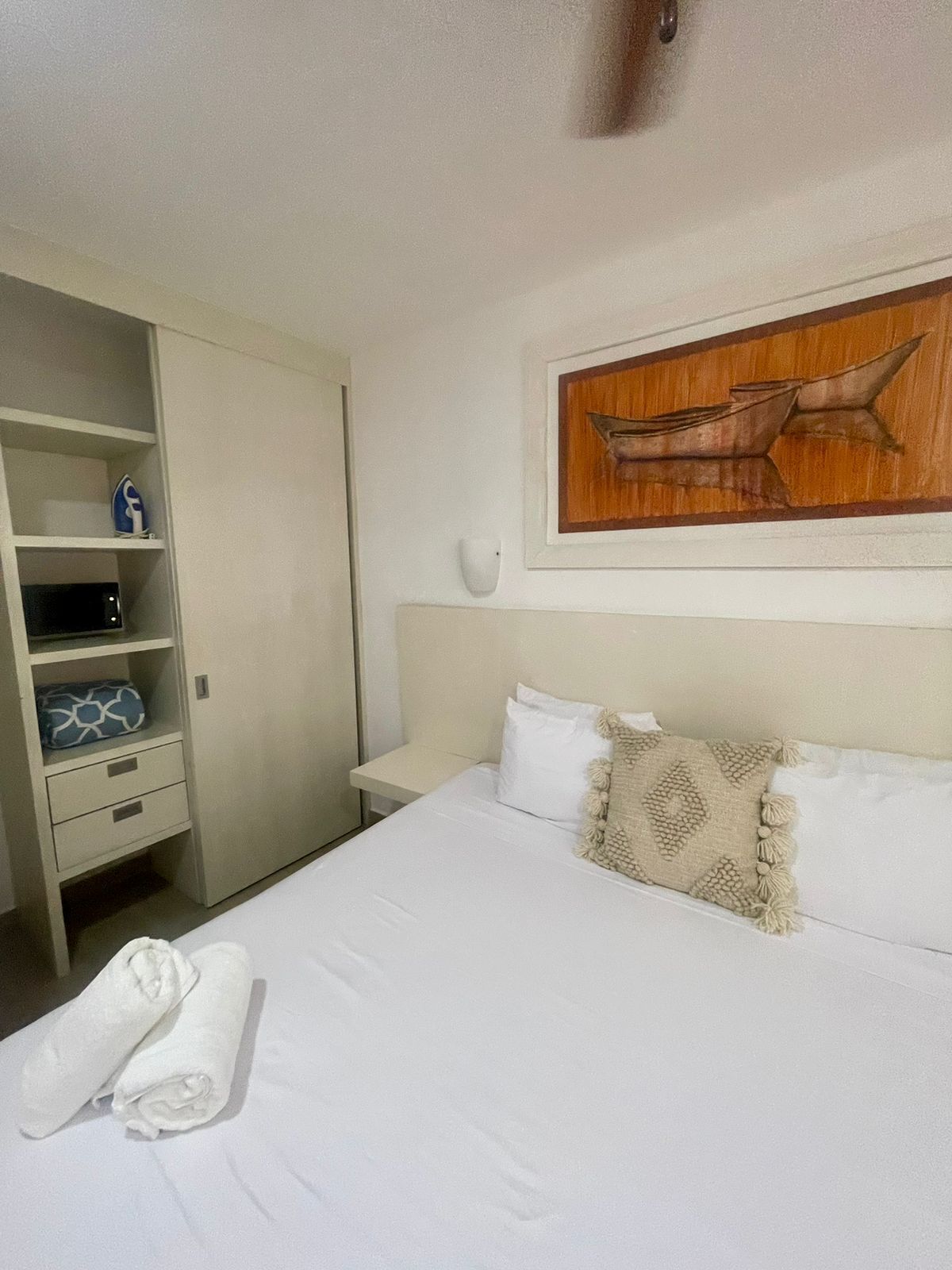 Een hotelkamer met een bed, een kledingkast, een nachtkastje en een kunstwerk aan de muur.