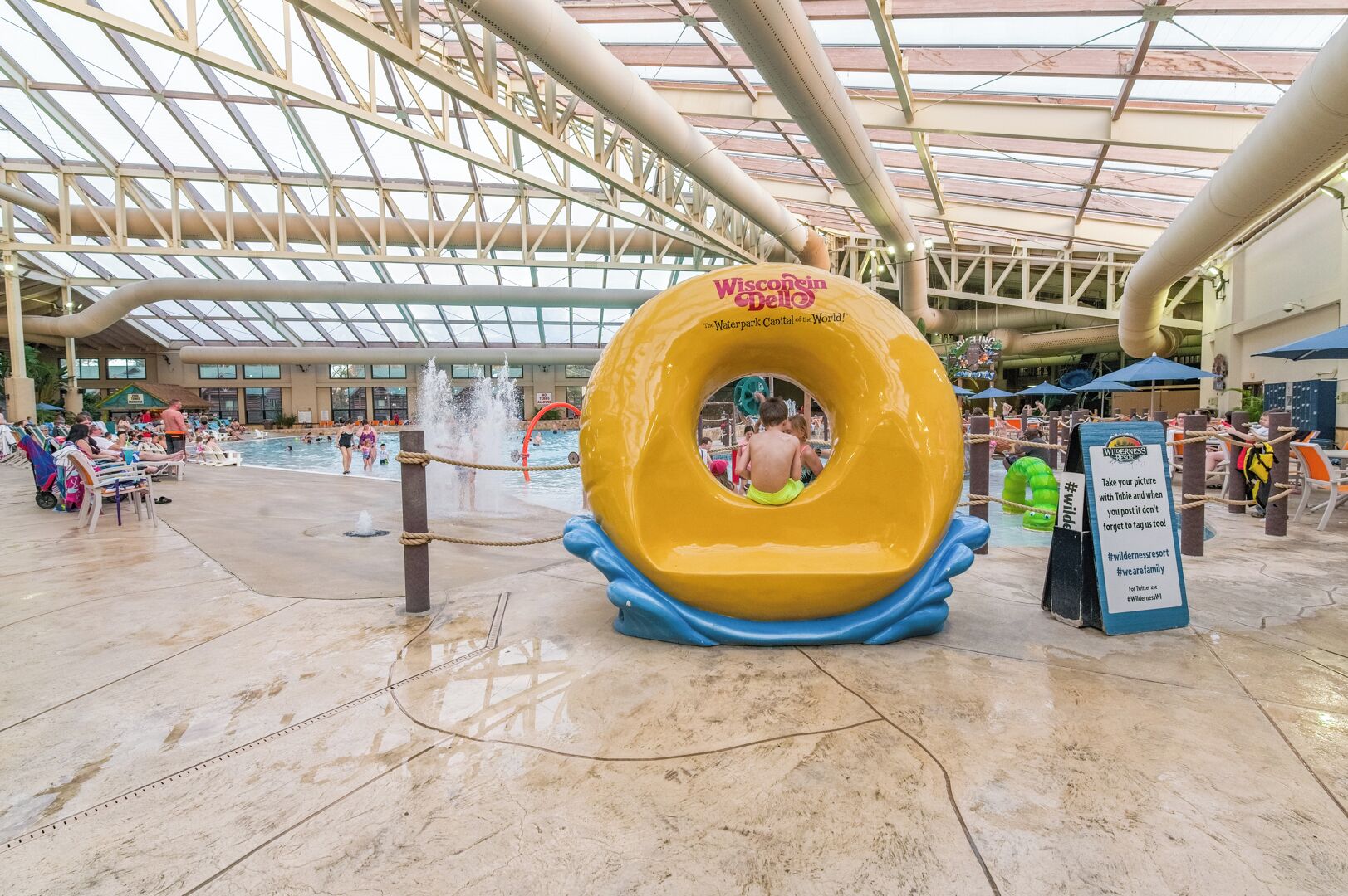 Un parc aquatique doté d’un grand toboggan jaune, d’une piscine et d’un espace couvert avec des sièges.