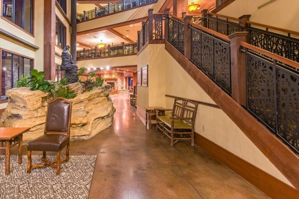 A spacious lobby with a grand staircase, seating areas, and a decorative rock feature.