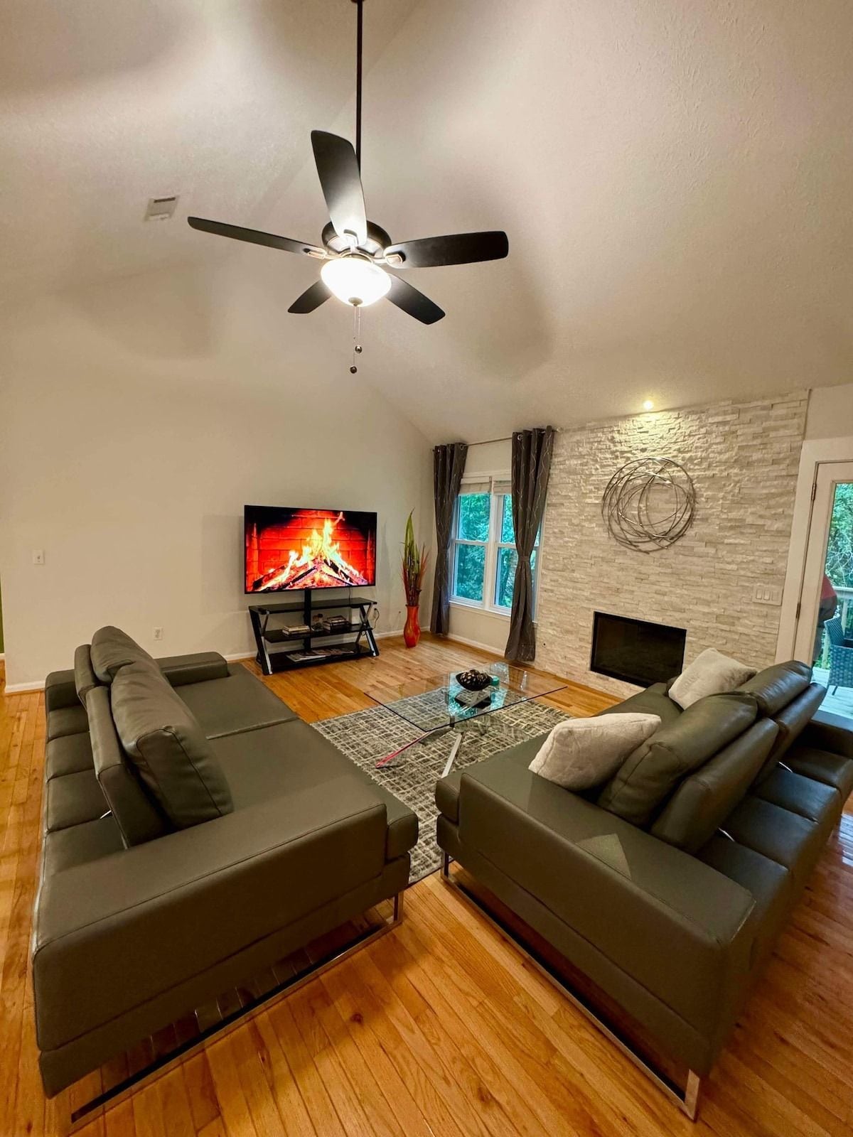 A modern living room with a fireplace, two sofas, a TV, and a ceiling fan.