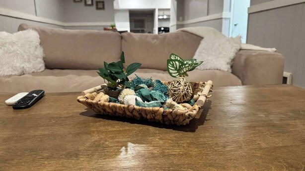 A wooden coffee table with a woven basket containing decorative items like a plant, seashells, and a woven ball. - The Amazing 4 Bed 2 Bath of Independence (Independence)