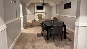 A cozy attic room with a dining table, chairs, a sofa, and a fireplace. - The Amazing 4 Bed 2 Bath of Independence (Independence)