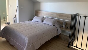 A bedroom with a bed, a nightstand, a lamp, and a radiator. - Casa Jardim Panoramic View (Estreito da Calheta)