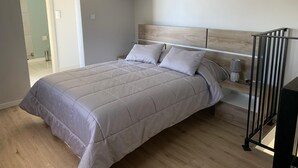 A bedroom with a bed, bedside table, lamp, and a view of the bathroom. - Casa Jardim Panoramic View (Estreito da Calheta)