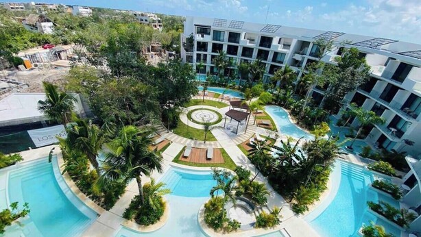 A hotel with a central pool surrounded by palm trees and a landscaped garden. - Super Studio Laguna C 106 (Tulum)