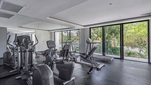 A modern gym with various exercise equipment, large windows, and a view of greenery outside. - Super Studio Laguna C 106 (Tulum)