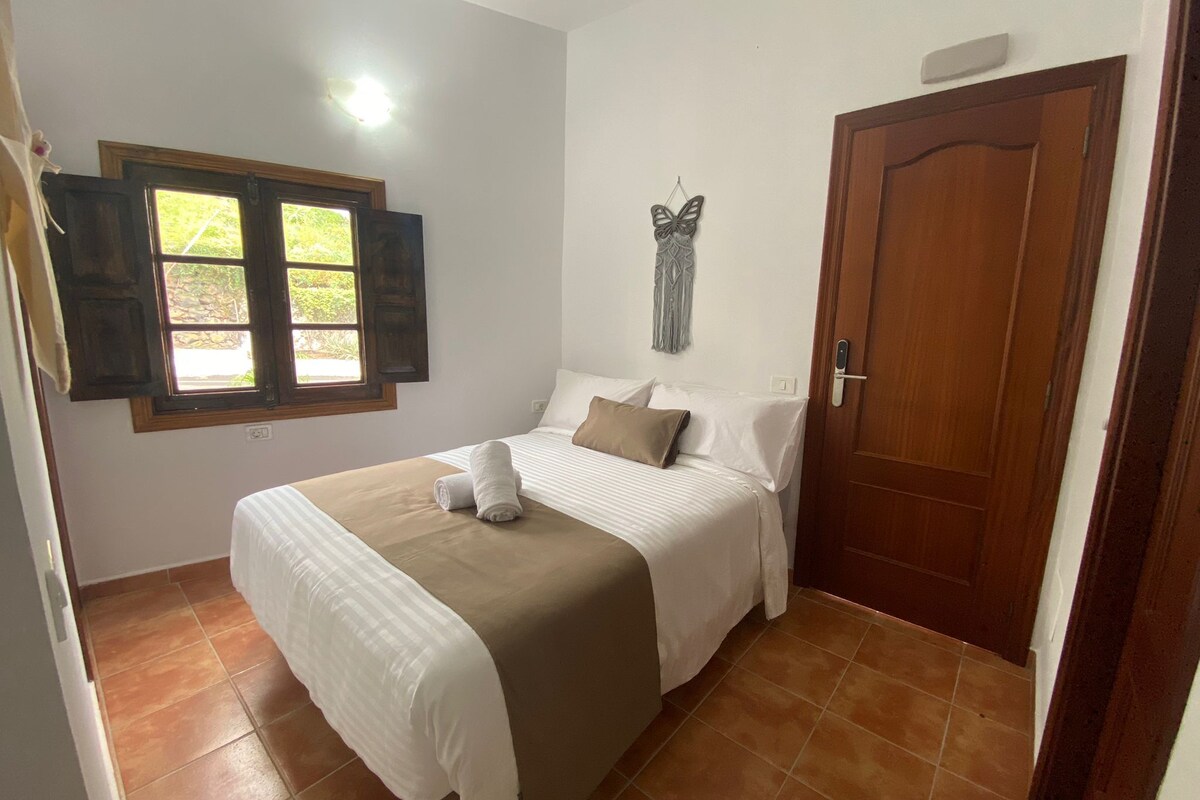 Une chambre à coucher avec un lit, une fenêtre, une porte et un élément décoratif mural.