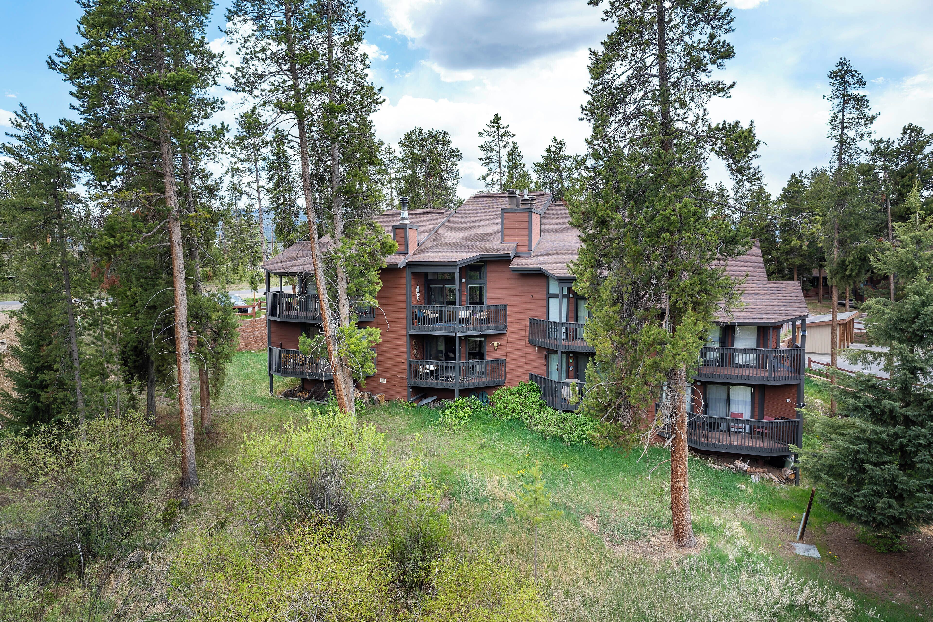 A multi-story building with balconies, surrounded by trees.
