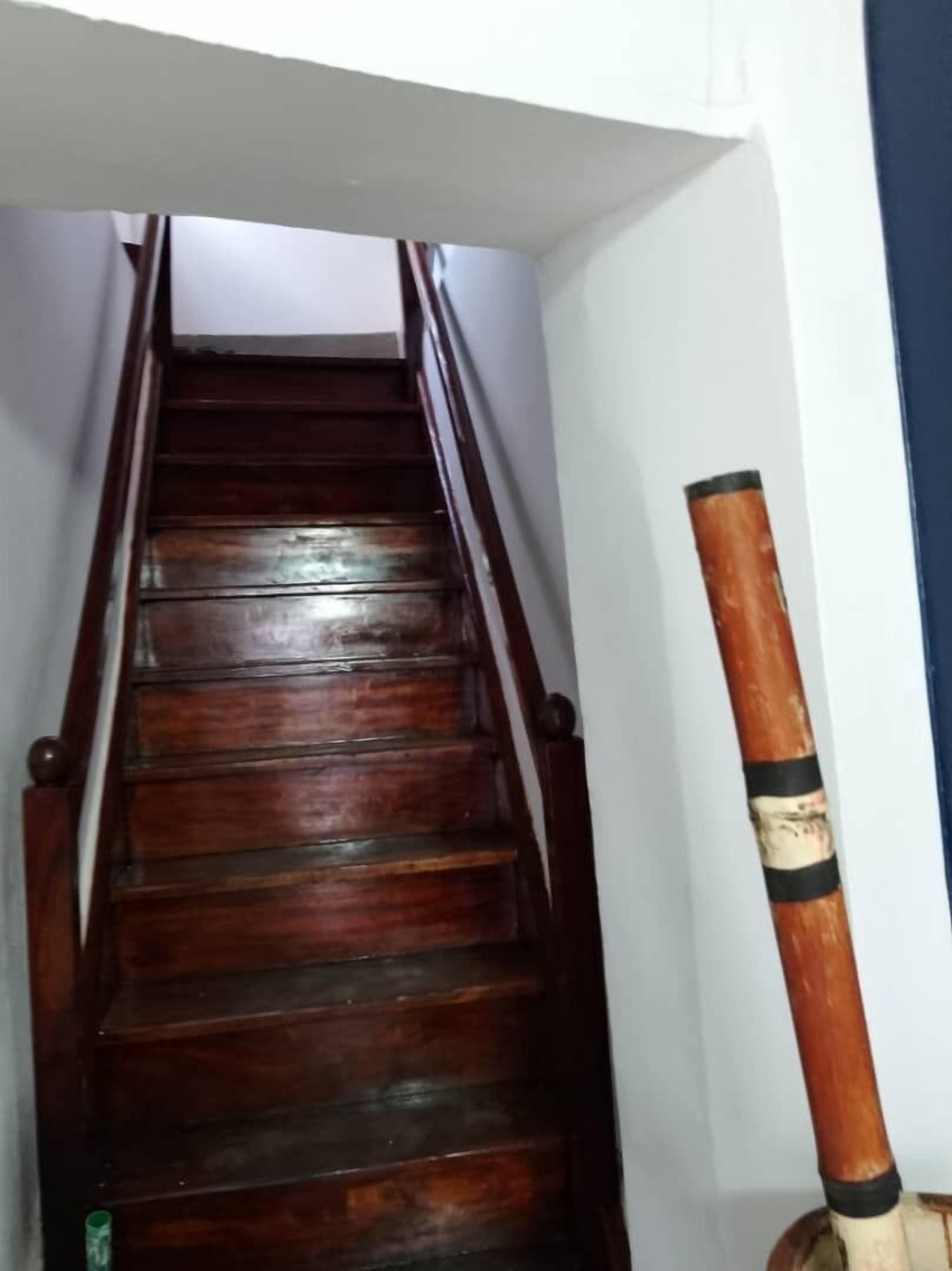 A wooden staircase with a handrail, leading to an upper floor.