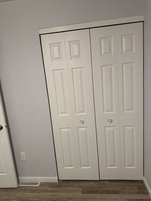 Puerta blanca cerrada con diseño sencillo, un respiradero en el suelo y una pared gris claro.