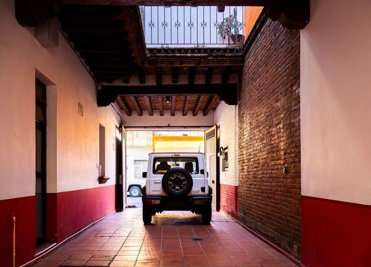A narrow alleyway with a white vehicle parked at the end.