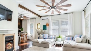 Una sala de estar moderna con chimenea, ventilador de techo y comedor.