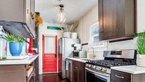 Una cocina moderna con armarios de madera oscura, electrodomésticos de acero inoxidable y una puerta roja.
