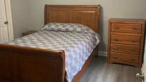 A bedroom with a wooden bed, a nightstand, a dresser, and a ceiling fan.