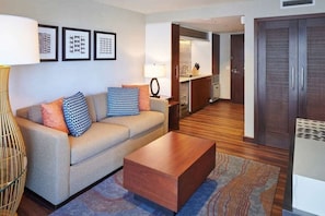 A living room with a sofa, coffee table, patterned cushions, a lamp, and a rug. - Waikiki | Couples Hawaii Beach Trip | Pool + Beach (Honolulu)