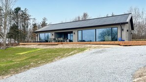 Een modern huis met een ruime garage, een overdekt terras en een oprit met grind.