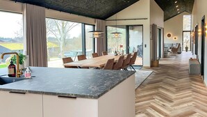 Een moderne keuken met een groot eiland, een houten eettafel en stoelen.