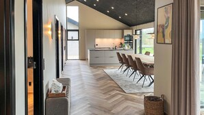 Een moderne keuken met een centraal eiland, een eethoek met stoelen en een visgraat parketvloer.