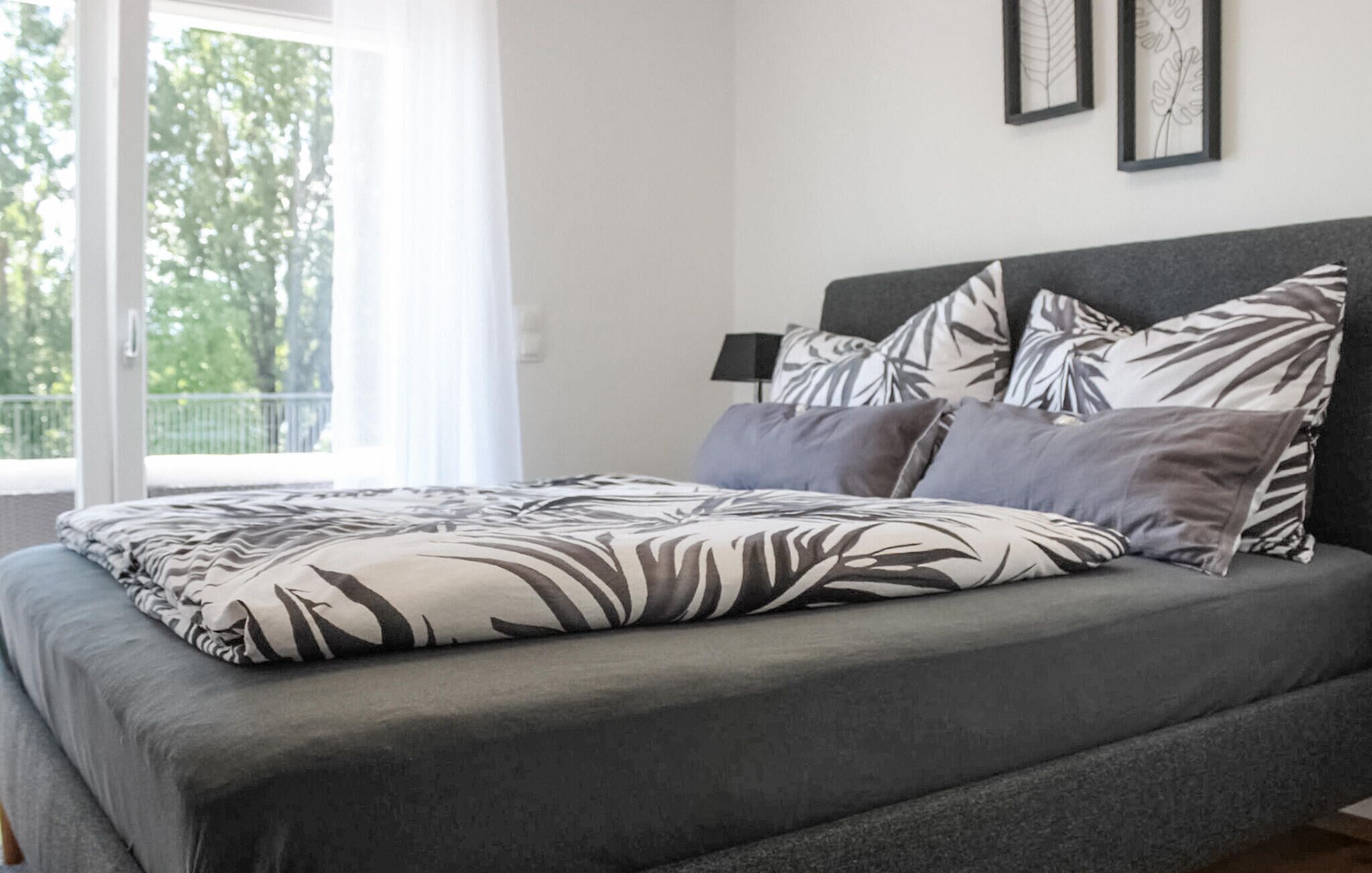A bed with a zebra print bedspread, a grey headboard, and multiple pillows.