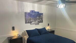 A bedroom with a bed, nightstands, a wall-mounted light fixture, and a ceiling fan. - Charming 2-bedroom house with AC and WiFi in lovely Wanette (Wanette)