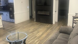 A modern living room with a fireplace, a sofa, and a glass coffee table. - Charming 2-bedroom house with AC and WiFi in lovely Wanette (Wanette)