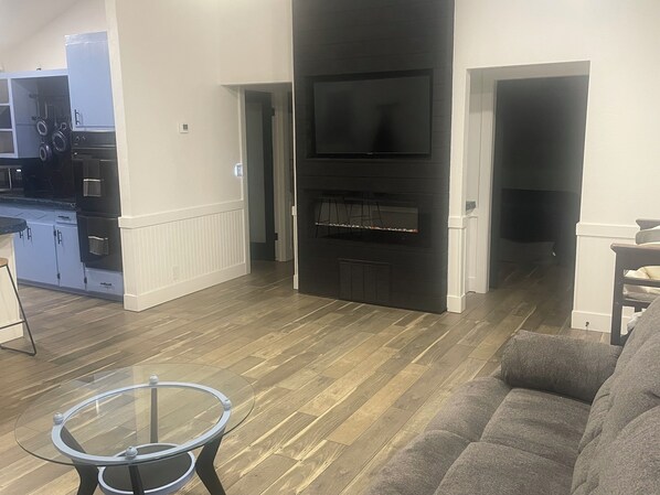 A modern living room with a fireplace, a sofa, and a glass coffee table.